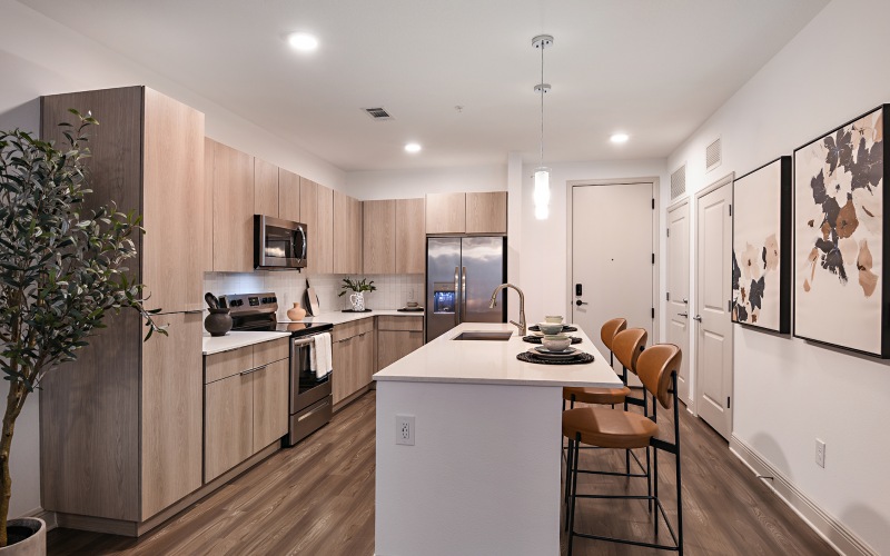 Spacious and well lit kitchen with wood floors and stainless steel appliances. 